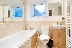ein Badezimmer mit einem WC und einem Waschbecken sowie zwei Fenster in der Unterkunft 3 Bedroom home close to town centre with WiFi & garden in Royal Tunbridge Wells