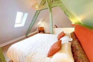a bedroom with a white bed with orange pillows at Appartement Moonrise - Plage 50m - Rue gratuite in Saint Malo