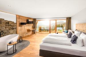 a bedroom with two beds and a bath tub at Hotel Bergflair in Fischen