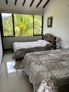 a bedroom with two beds and a large window at Casa ambiente rural La Vega Cundinamarca in La Vega