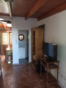 a living room with a flat screen tv and a table at Cabañas Farah Estancia Vieja ideal para 2 a 3 huéspedes in Villa Carlos Paz