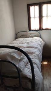 a bed with white sheets in a room with a window at Cabañas La Oma Intiyaco in Atos Pampa