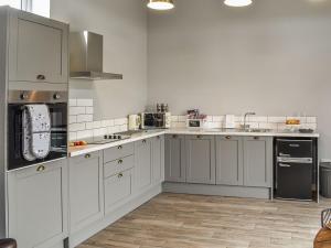 a kitchen with white cabinets and stainless steel appliances at Sheepfold Cottage in Eccleshall