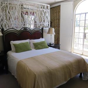 a bedroom with a large bed with green pillows at Marrakech Guest House in Bloemfontein