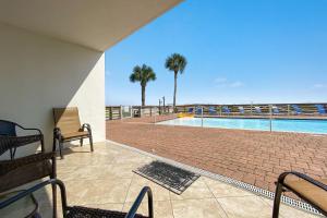 a patio with a swimming pool and palm trees at SeaSpray West 105- Gulf Front in Perdido Key