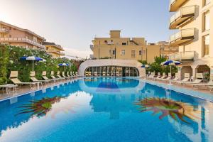 une grande piscine avec des chaises et des parasols dans l'établissement Universal Hotel, à Cervia