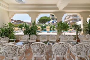 un restaurant avec des chaises blanches, des tables et des fenêtres dans l'établissement Universal Hotel, à Cervia