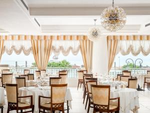 a dining room with tables and chairs and chandeliers at Universal Hotel in Cervia