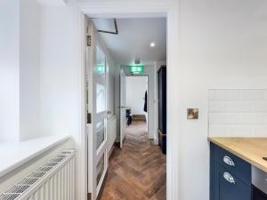 a kitchen with blue cabinets and a hallway at Driftwood Boutique Guest House in Rhosneigr