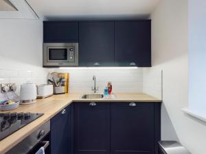 a kitchen with navy blue cabinets and a sink at Driftwood Boutique Guest House in Rhosneigr