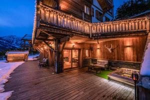 a large wooden house with a deck in the snow at Luxury chalet Léli in Saint-Chaffrey
