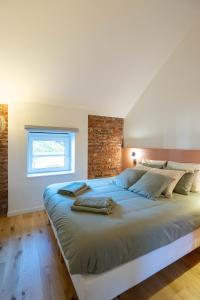 een slaapkamer met een groot bed met een bakstenen muur bij Ardn-bnb Bike n Bed in La-Roche-en-Ardenne