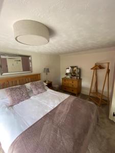 a bedroom with a large white bed and a lamp at Curlew Cottage in Sedgeford