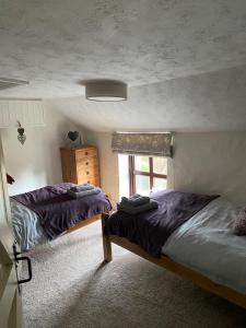 a bedroom with two beds and a window at Curlew Cottage in Sedgeford