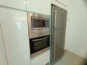 a kitchen with a stainless steel refrigerator and a microwave at Pax 6+3 Grand Lux Melaka homestay in Melaka