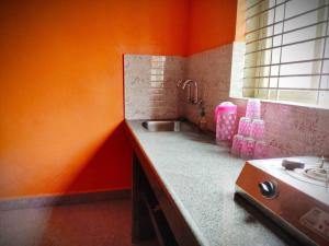 an orange kitchen with a sink and a window at Kamanabillu Homestay, For jog falls travellers in Siddāpur