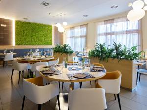 リーヴァ・デル・ガルダにあるGarda Sporting Club Hotelのテーブルと椅子、植物のあるレストラン