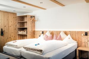 Schlafzimmer mit einem großen weißen Bett und Holzwänden in der Unterkunft Pension der Steinbock - das 300 Jahre alte Bauernhaus - TIROL in Sankt Anton am Arlberg