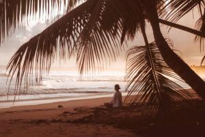 una mujer sentada en la playa mirando el océano en 3 Bedroom Pool Villa 50M To The Beach, en Las Terrenas