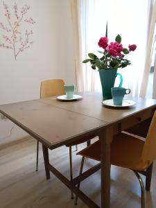 una mesa de madera con dos tazas y un jarrón con flores. en Il Torrione, en Guardiagrele