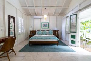 a bedroom with a bed and a desk and windows at Fond Doux Eco Resort in Soufrière