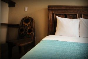 a bed with a wooden headboard and a chair in a room at Residencia San Pablo in Querétaro