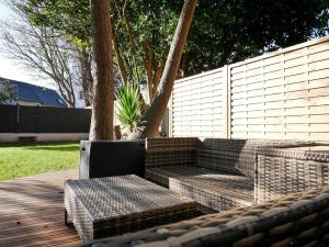 un patio avec deux bancs sur une terrasse en bois dans l'établissement CLINT HOUSE - Appartement "Jardin de granit rose", à Perros-Guirec