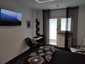 a bedroom with a bed and a desk and a television at Black & White Apartment in Saarbrücken