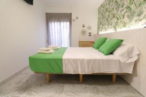 Un dormitorio con una cama con almohadas verdes. en 203 I Posada del Mar I Encantador hostel en la playa de Gandia, en Los Mártires