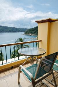 una mesa y sillas en un balcón con vistas al agua en Camino Real Acapulco Diamante en Acapulco