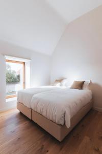 una camera bianca con un grande letto e una finestra di Vakantiewoning Duisbeke Logies a Oudenaarde
