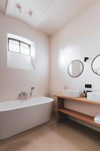 a bathroom with a tub and a sink and mirrors at Vakantiewoning Duisbeke Logies in Oudenaarde