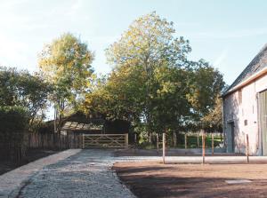 uma estrada de terra ao lado de um celeiro com árvores e uma cerca em Vakantiewoning Duisbeke Logies em Oudenaarde