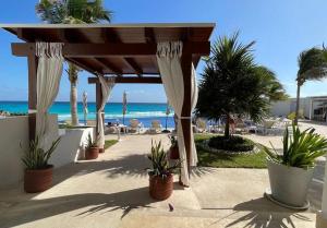a pavilion at the beach with chairs and palm trees at Ocean Dreams by Andiani Travel in Cancún