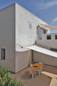 un patio con una mesa de madera y un edificio en Nesea Domus, en Marina di Ragusa