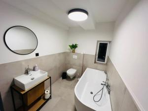 een badkamer met een bad, een wastafel en een spiegel bij Traumhaus•7Beds•CoWorking•Wifi•3ParkingSpaces in Erwitte