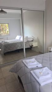 1 dormitorio con paredes de espejo y 1 cama con toallas en Departamento con pileta, balcón y parrilla en Salta