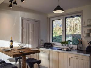 a kitchen with a table and a sink and a window at Ardmhor in Balquhidder