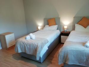 a bedroom with two beds and two lamps on tables at Carvetii - Iona House, 2nd floor apartment sleeps up to 6 in Kirkcaldy