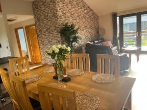 een houten eettafel met stoelen en bloemen erop bij Cheerful 3-bedroom cabin with hot tub in Kings Lynn