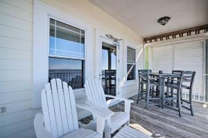 a porch with white chairs and a table on it at Oceanfront Oasis in Cedar Key with 2 Balconies! in Cedar Key