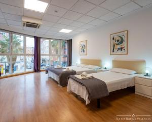 2 łóżka w pokoju z drewnianymi podłogami i oknami w obiekcie Suites Rooms Valencia w Walencji