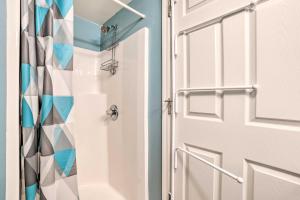 a white door with a shower curtain in a bathroom at Portage Lake Condo with Deck and Pool Access! in Onekama