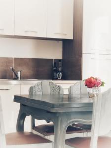 einen Tisch in einer Küche mit weißen Schränken und Blumen darauf in der Unterkunft Stableyard cottages in Lamorlaye