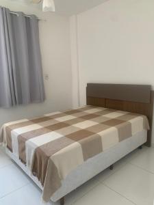 Un dormitorio con una cama con una manta a cuadros. en Apto 2 Quartos Perfeito, en Guarapari