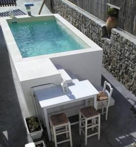 a swimming pool with a table and chairs next to at Seafarer's House. Ideal for 3+1 guests in Mikonos