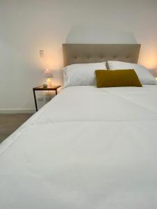 ein Schlafzimmer mit einem großen weißen Bett und einem gelben Kissen in der Unterkunft Amazing 2BR in Barranco in Lima