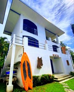 une maison blanche avec une planche de surf orange devant elle dans l'établissement Show Pony Beach Resort and Suites, à Las Lajas