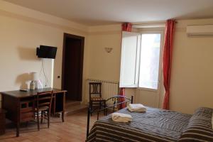 1 dormitorio con cama, escritorio y ventana en Locanda Fosca Umbra, en Narni
