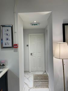 a hallway with a white door and a lamp at Elegant 2 Bed Flat in Chiswick in London